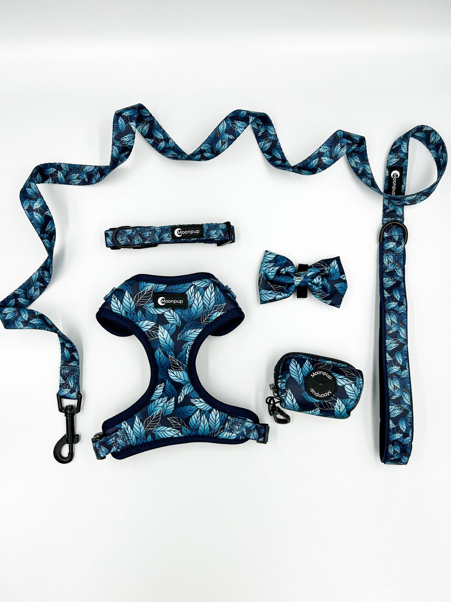 Setul complet Blue Jungle de la Moonpup pentru câini – include ham, zgardă, lesă fixă, fundiță și suport de saci, toate cu un design tropical vibrant. Manerul captușit al lesei asigură confortul stăpânului, iar inelul pentru suportul de saci adaugă funcționalitate. Perfect pentru plimbări elegante și plăcute împreună cu patrupedul tău.